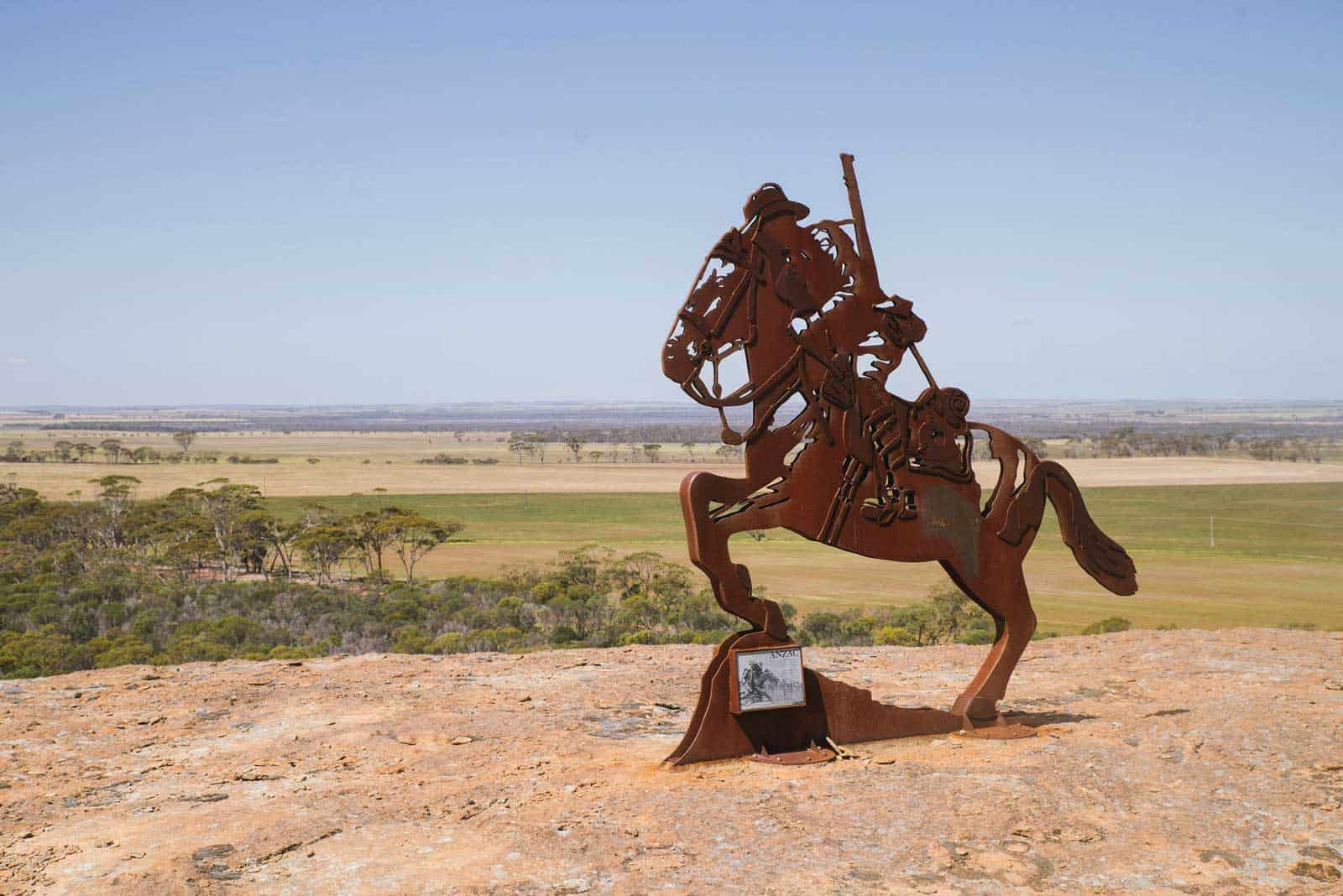 Sculpture of a horse and soldier on top of a rock overlooking a field on the self drive trail Pathways to Wave Rock