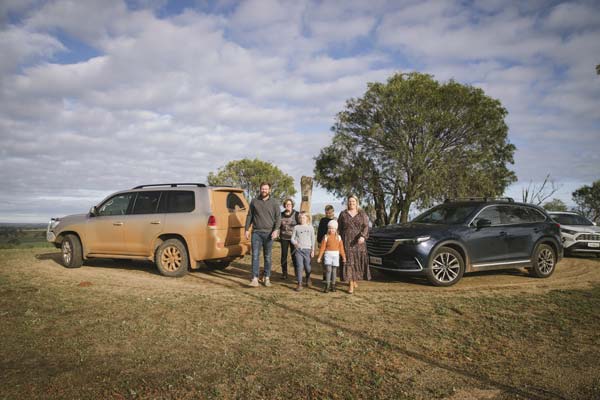 Image of a young family standing in front of their 4WD vehicles in field