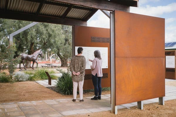 Image of two woman looking at historical walk trail signage in Narembeen